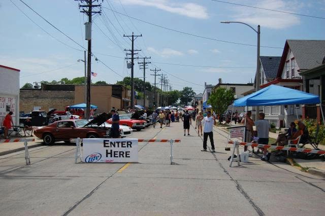 The Enter Here barricade at the street entrance to the car show, classic cars parked along the block
