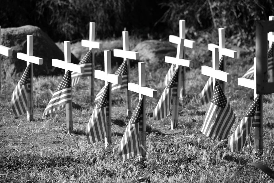 American flags standing among white crosses at a military cemetery