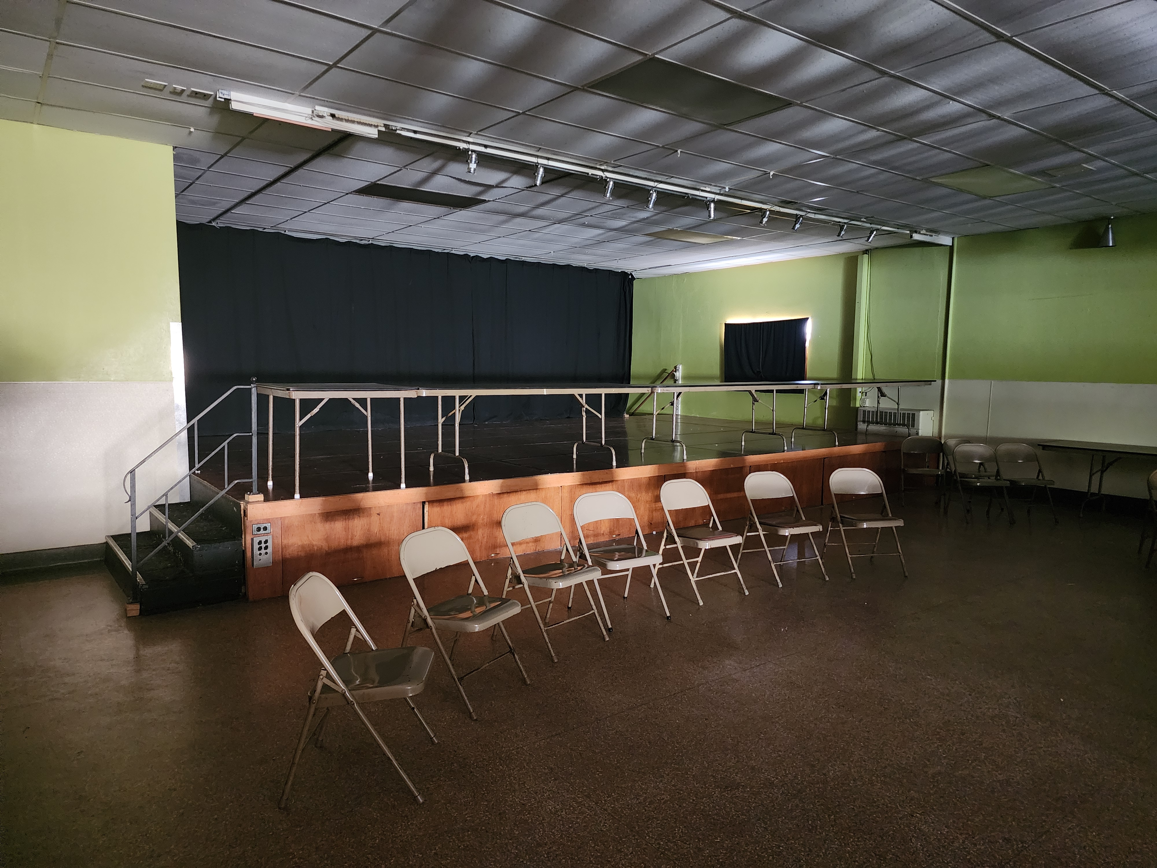 The hall stage with its black curtain, handrail and steps up from the floor