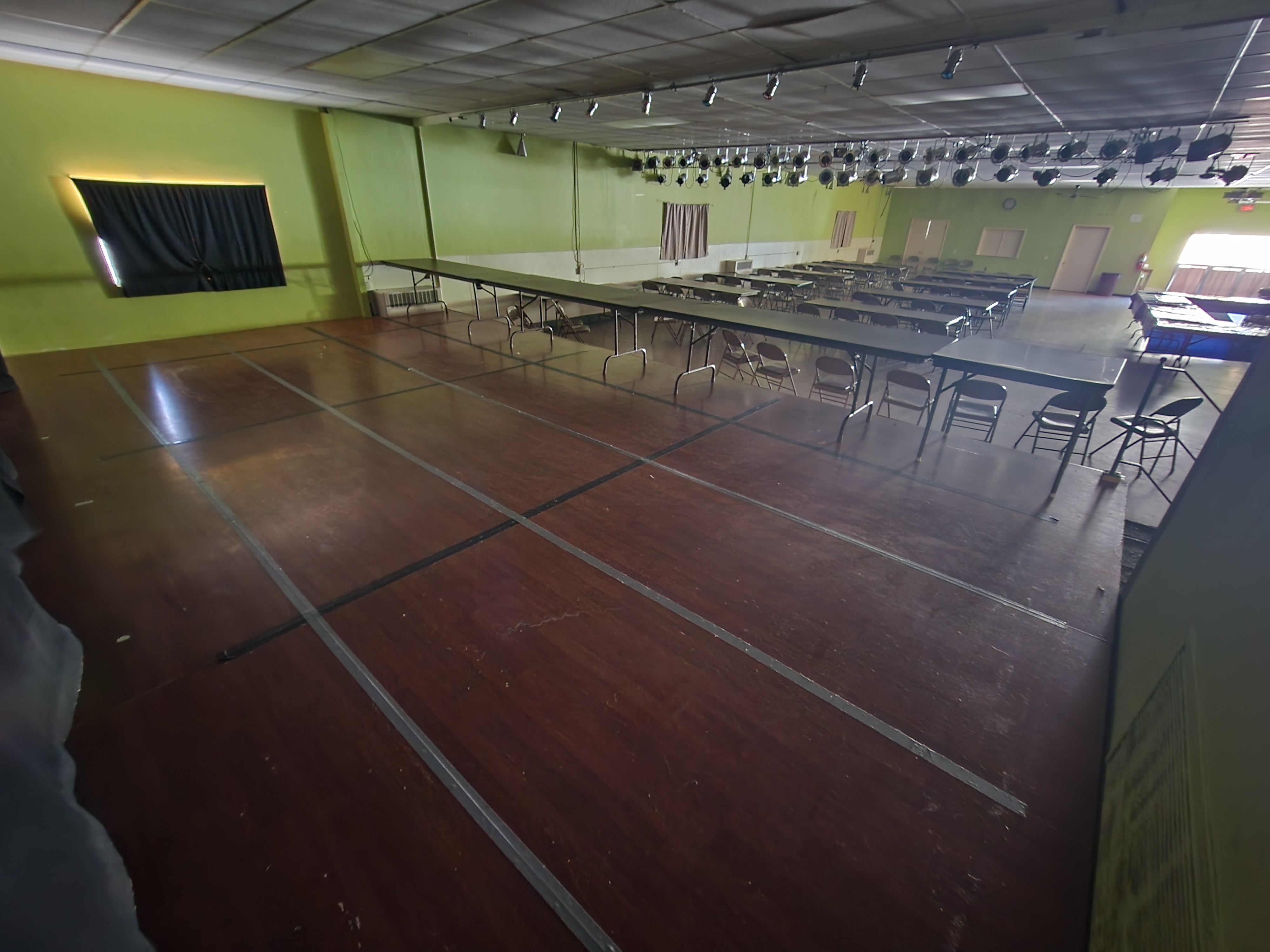 The upper hall's wooden dance floor with the stage lighting rig overhead and banquet tables beyond