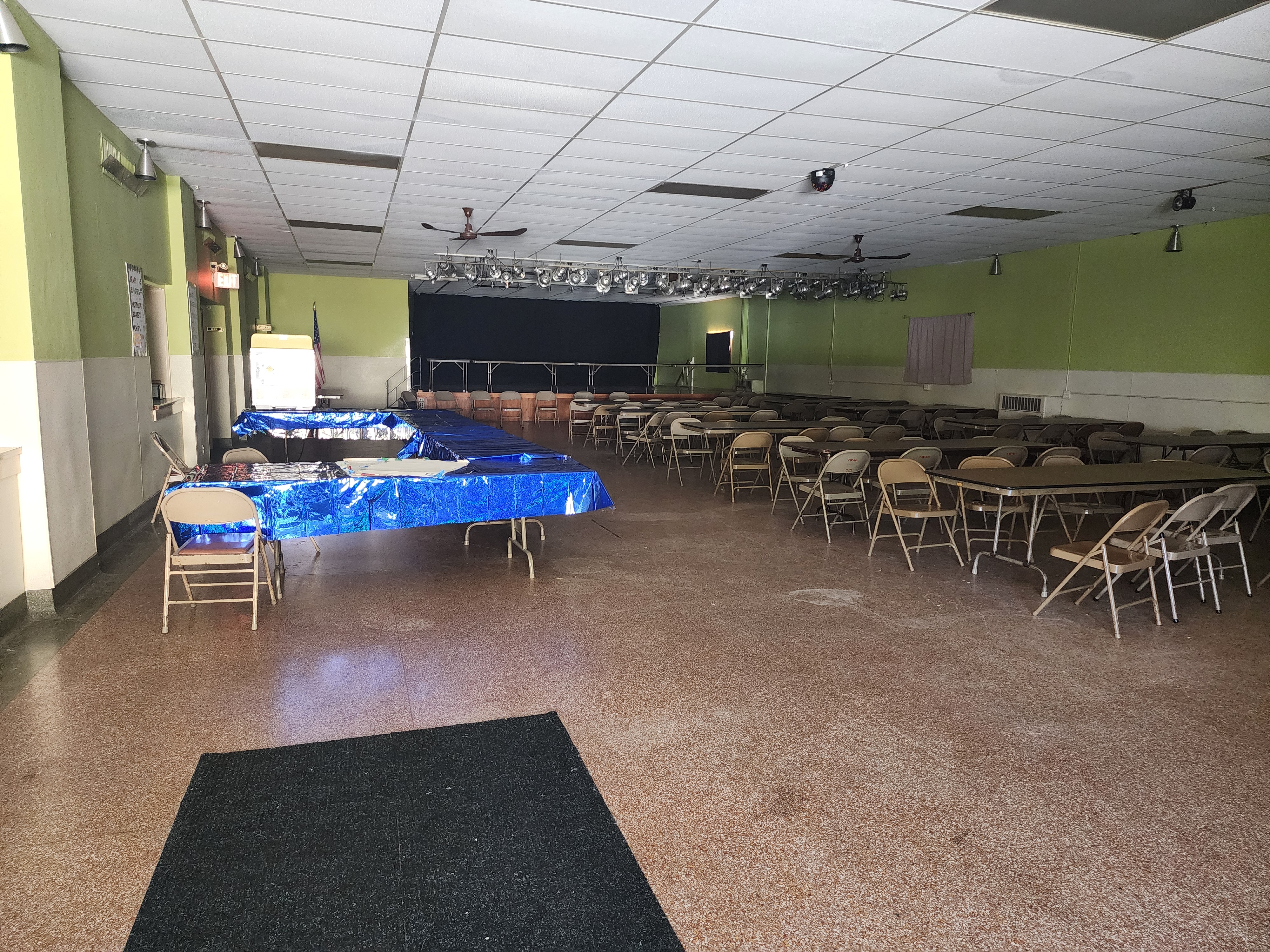 The upper event hall set with banquet tables and chairs, the stage and its lighting rig at the far end